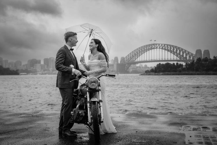 Black & white photo of couple with motorbike on Sydney Harbour by Fiona & Bobby