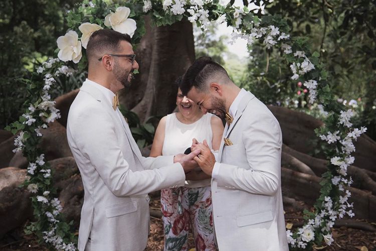 Ingrid Winter officiating a gay wedding ceremony amongst lush green gardens